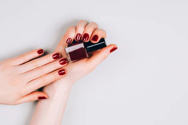 Piękny Ciemnoczerwony Manicure Lakierem Paznokci Dłoniach Szarym Tle Strzał Makro — Zdjęcie stockowe