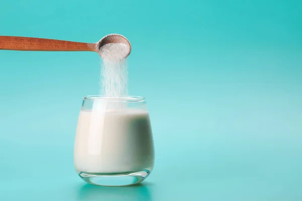 stock image Coconut or almond milk with collagen sponon blue background with palm leaf