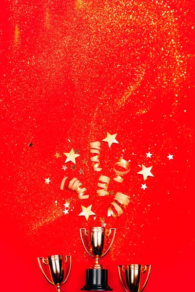 Három Arany Kupa Piros Hátterű Konfettivel Lapos Fekvésű Versenykoncepció — Stock Fotó