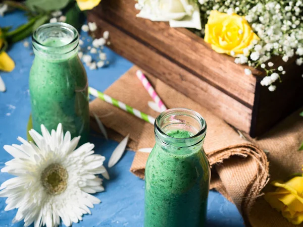 Batido verde en botellas de vidrio con flores — Foto de Stock