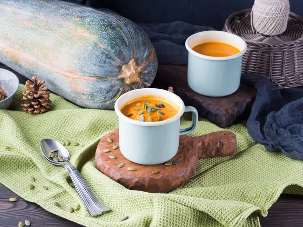 Pumpkin cream soup in enamel mugs. Rustic lunch