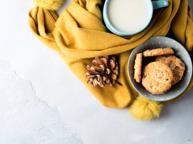 Mug of tea with milk and cookies in winter scarf. Top view clipart
