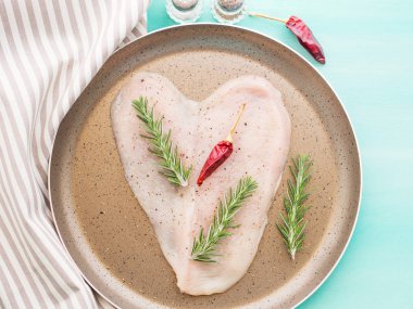 Kalp şeklinde otlar ve biber ile çiğ tavuk göğsü