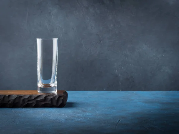 Dunkelschwarzer Hintergrund mit leerem Glas auf Holzbrett — Stockfoto