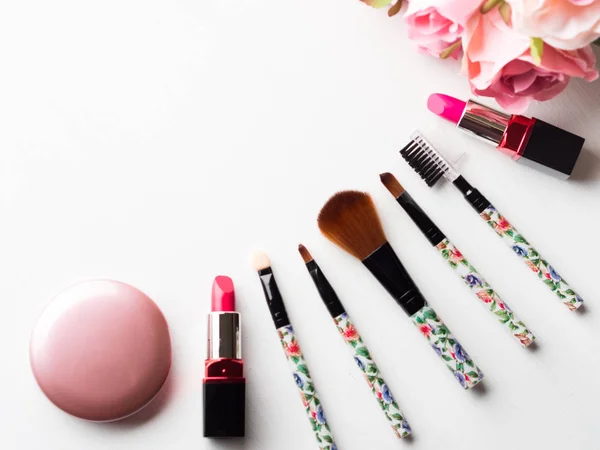 Maquiagem de produtos e ferramentas com flores de rosas rosa em branco — Fotografia de Stock