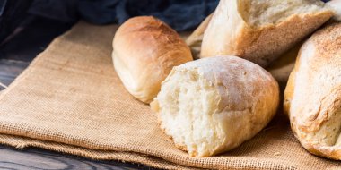 Çuval bezi koyu ahşap arka plan üzerinde taze pişmiş ekmek