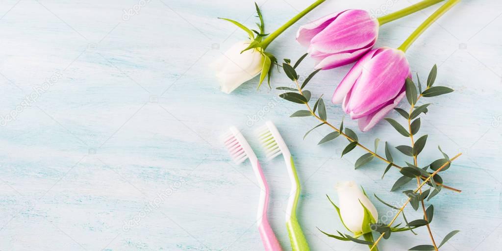 Two pastel toothbrushes with flowers herbs. Spring colors