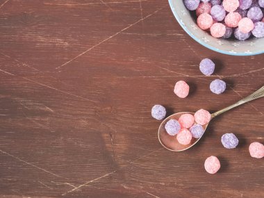 Mor ve pembe şekerler kase ahşap arka plan üzerinde