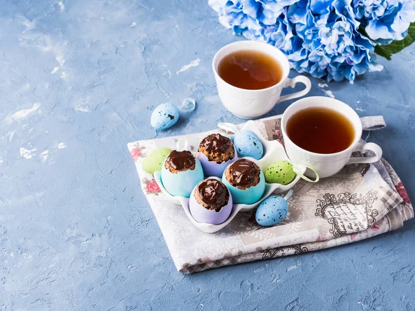 Pasteles dulces de Pascua en cáscaras de huevo de colores sobre azul — Foto de Stock