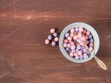 Mor ve pembe şekerler kase ahşap arka plan üzerinde