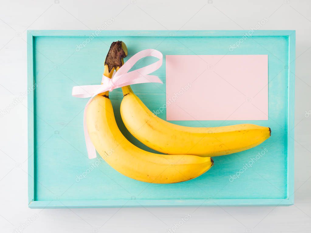 Two bananas with pink ribbon and card