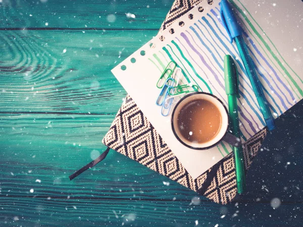 Cup of coffee, notebook and pen on dark