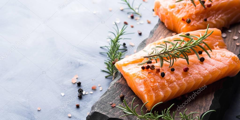 Raw salmon on wooden board with herbs