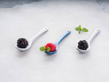 Üzerinde gri arka plan üzerine kaşık taze çilek