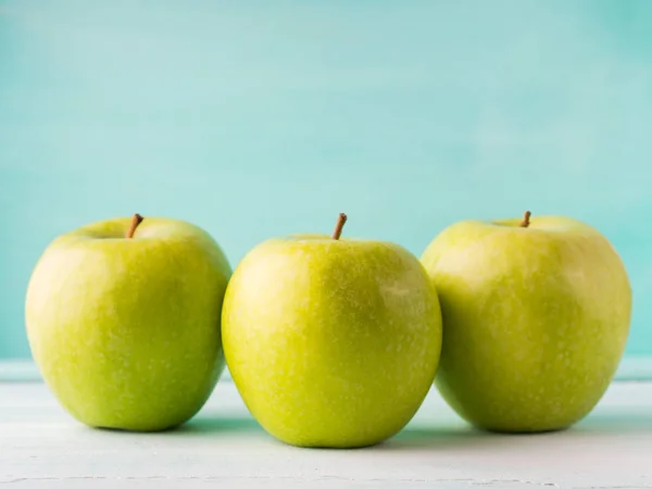 Three Green apples on turquoise background — Stock Photo, Image