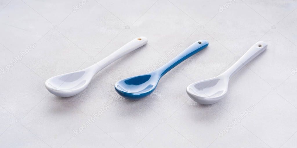 Three empty spoons on gray background