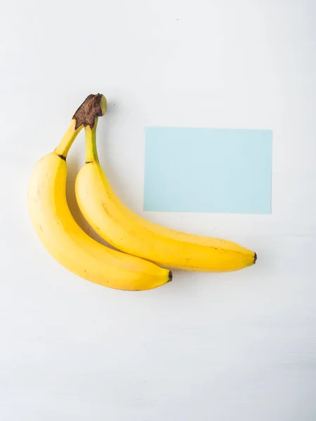 Duas bananas em branco com cartão azul — Fotografia de Stock