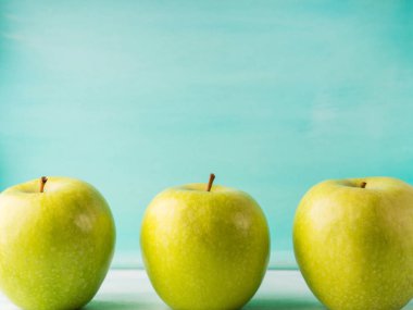 Turkuaz arka plan üzerinde üç yeşil elma