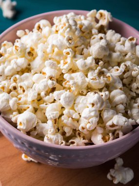 Koyu arka plan üzerinde pembe kase patlamış mısır