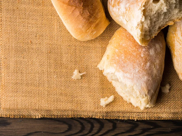 Frissen sült kenyeret, zsákvászon sötét fából készült háttér — Stock Fotó