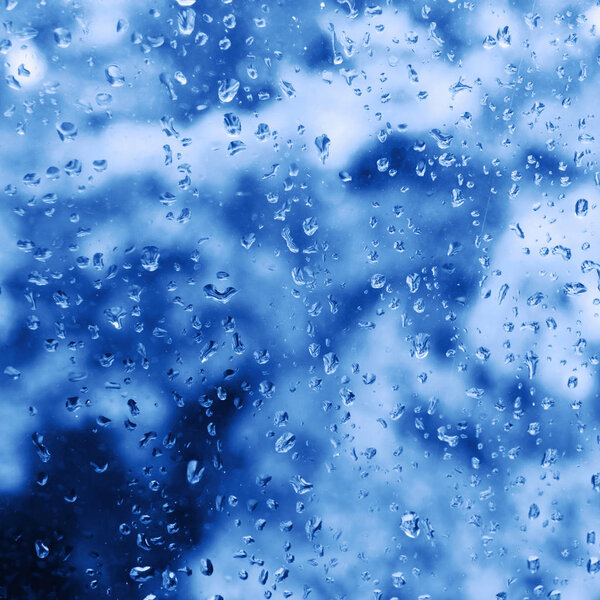 Rain drops on the window glass. Classic blue tone