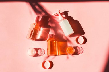 Pembe mercan üzerinde çeşitli kozmetik ürünler. Düz yatıyordu