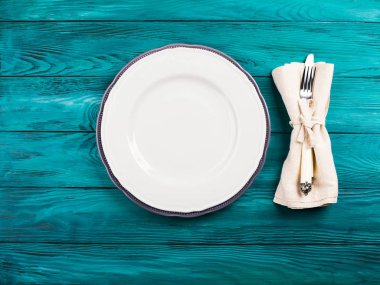 Boş beyaz tabak ve çatal bıçak takımı ahşap masada.