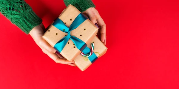 Caja de regalo con cinta verde en manos femeninas en rojo —  Fotos de Stock