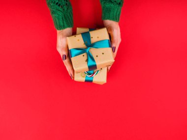 Yeşil kurdeleli hediye kutusu. Kırmızı ellerde kadın eli.