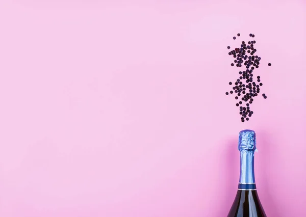 Garrafa de champanhe e fluxo de confete em rosa — Fotografia de Stock