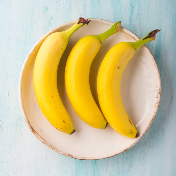 Tre banane su un piatto di turchese verde — Foto Stock