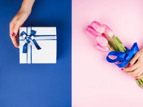 粉红蓝两色上有郁金香的女性手和礼物 — 图库照片
