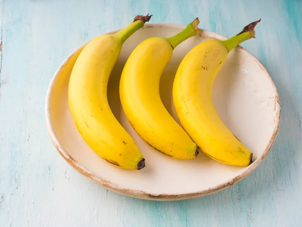 Tre banane su un piatto di turchese verde — Foto Stock