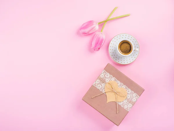 Cup coffee, gift box and tulips on pink backdrop