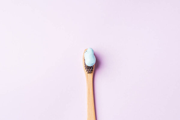 Bamboo toothbrush with blue toothpaste on pink