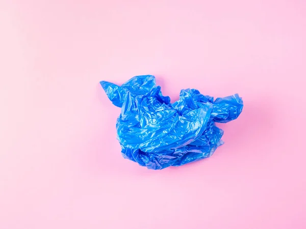 Збитий синій пластиковий мішок для сміття на рожевому фоні — стокове фото