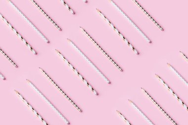 White and golden pencils pattern on pink pastel
