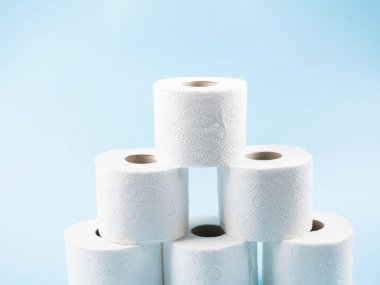 Bir yığın tuvalet kağıdı mavi arka planda yuvarlanıyor.