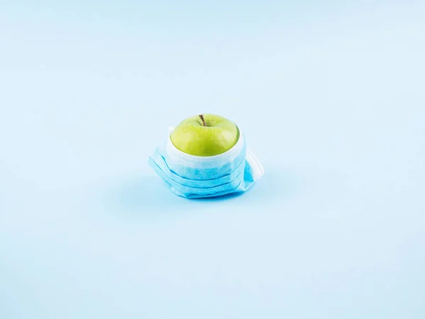 Zelené čerstvé jablko v masce. Covid19 koncept — Stock fotografie
