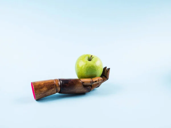 Čerstvé zelené jablko v dlani z dřevěné ruky na modré — Stock fotografie
