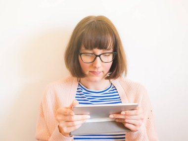 Gözlüklü gülümseyen kız tablet kullanıyor.