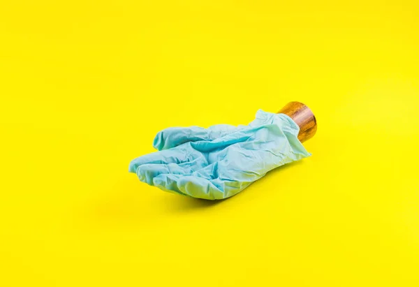 Дерев'яна рука в синій рукавичці на жовтому. Ковід19 — стокове фото