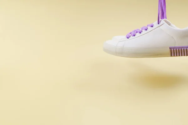 White sneakers with purple laces on beige background