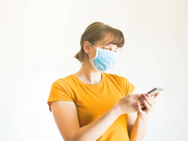 Junge Frau mit Gesichtsmaske nutzt Smartphone — Stockfoto