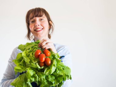 Elinde taze ürünlerle mavi önlüklü kadın.