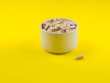 Sarı arka planda kapsüllerdeki Maca tozu