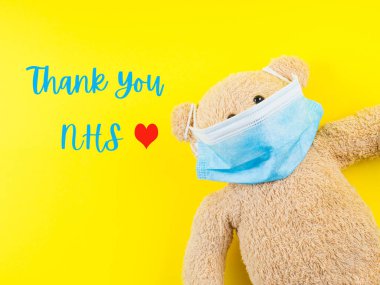 Maskeli oyuncak ayıyla NHS personeli için teşekkür kartı.