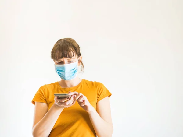 Junge Frau mit Gesichtsmaske nutzt Smartphone — Stockfoto