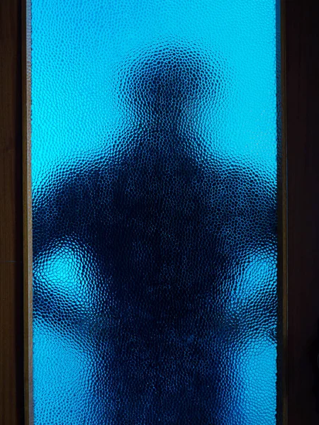 Człowiek w czerni za zamkniętymi drzwiami przez szkło — Zdjęcie stockowe