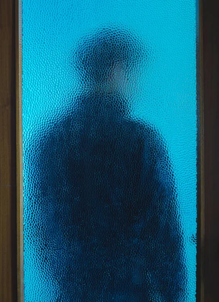 Hombre en negro detrás de la puerta cerrada a través de vidrio — Foto de Stock